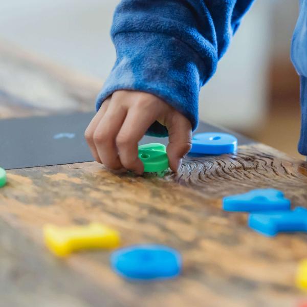 A child's hands manipulating colorful plastic letters and numbers