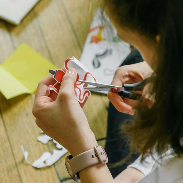 Top view of person with medium-length brown hair cutting out items for a craft project