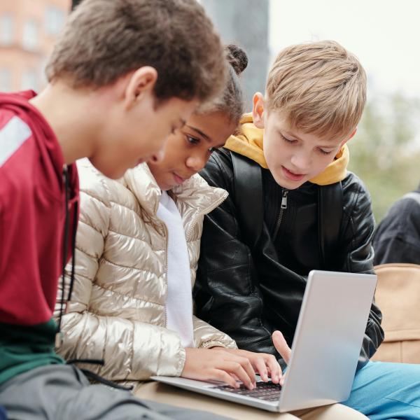Kids working together on laptop outside