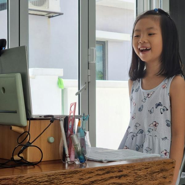 Young girl standing and presenting on laptop on desk