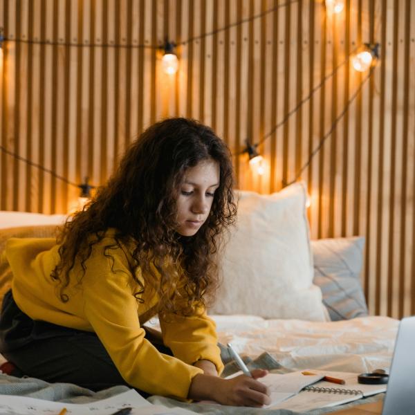 Teen working on homework in bedroom with warm lighting