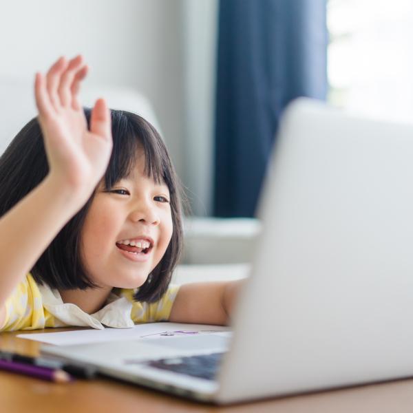 Little girl waving and smiling at laptop