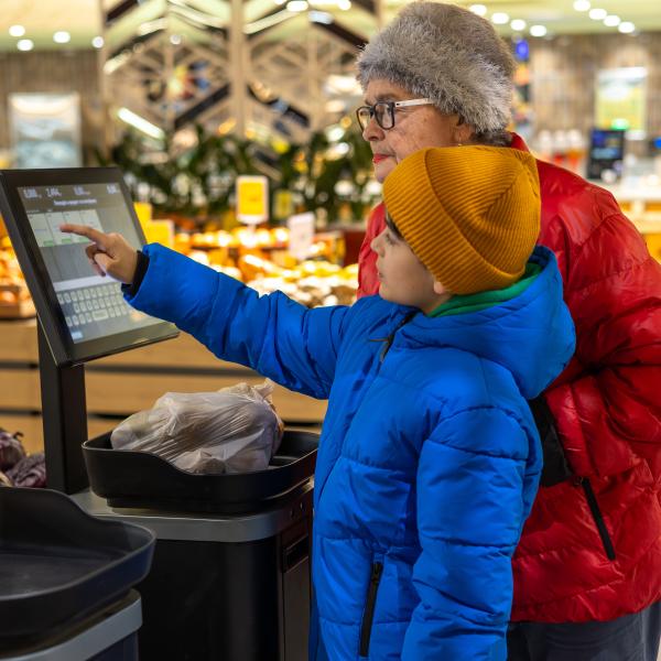 Kid helping adult at grocery self checkout
