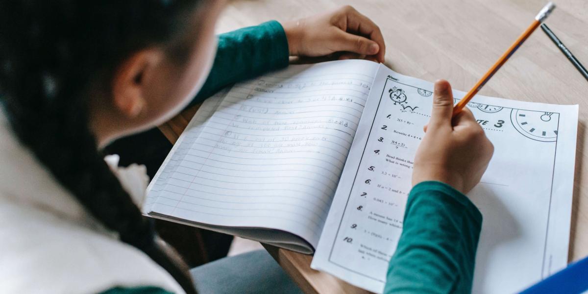 Top view of child with long braided pigtails filling out a worksheet