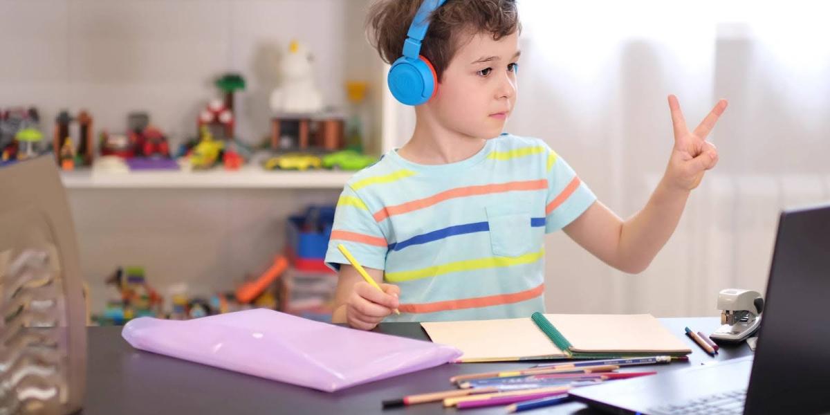 elementary virtual school child looking at laptop screen and showing 2 fingers up