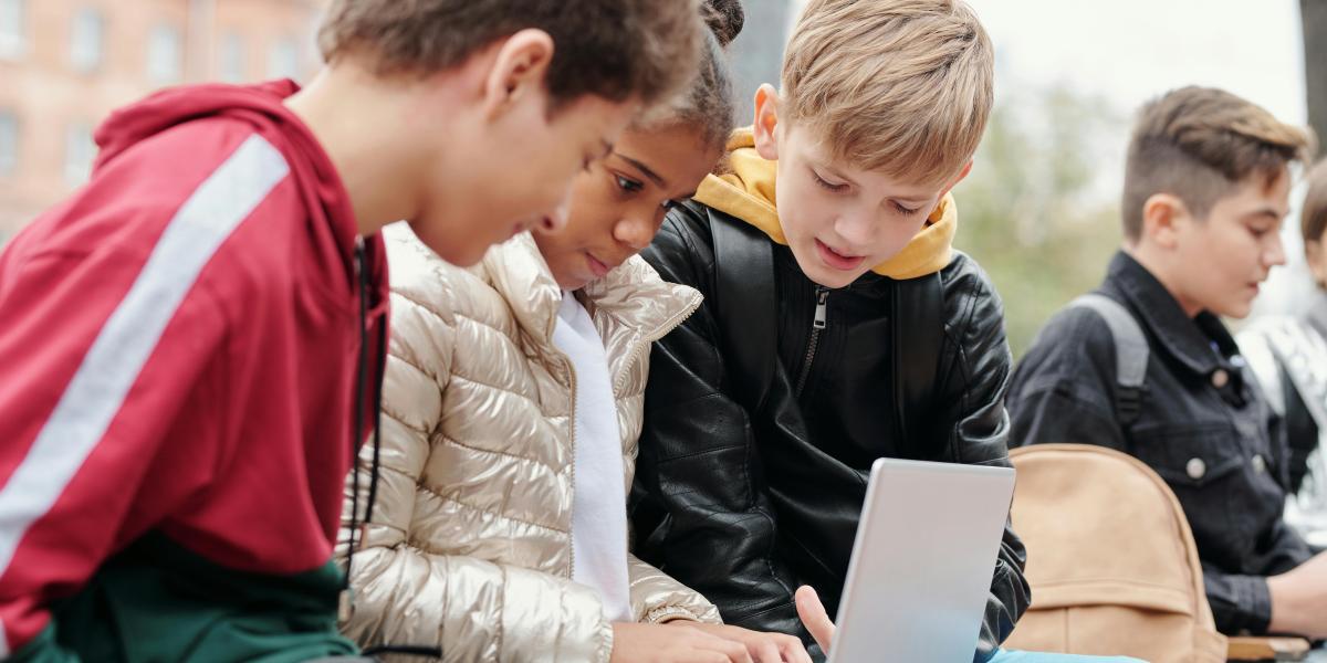 Kids working together on laptop outside
