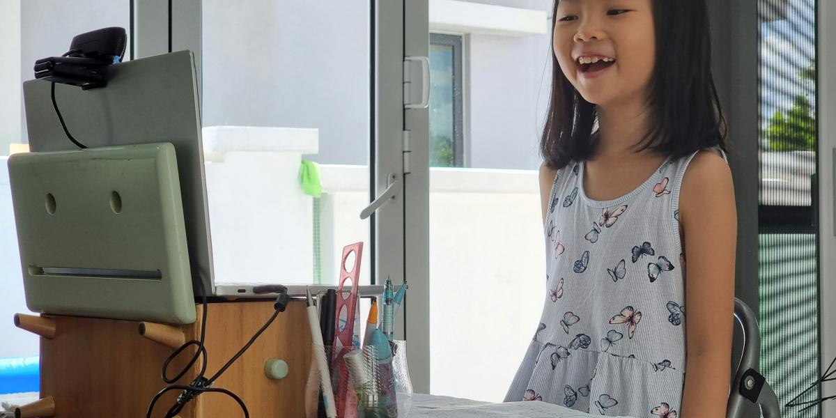 Young girl standing and presenting on laptop on desk