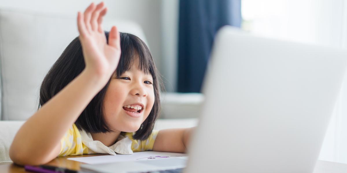 Little girl waving and smiling at laptop