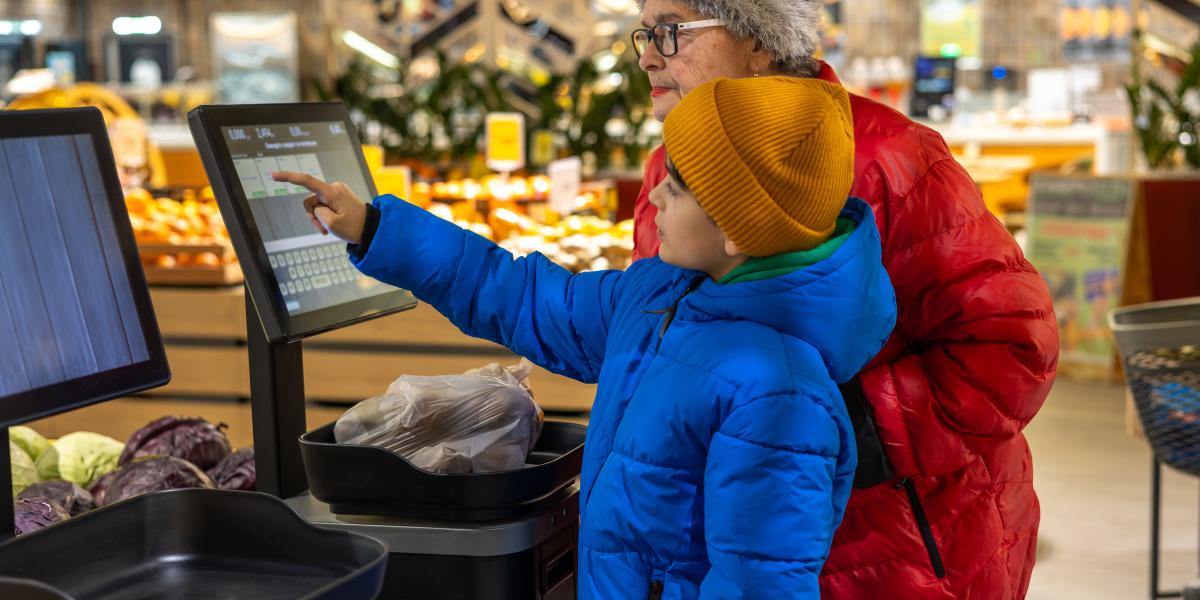 Kid helping adult at grocery self checkout
