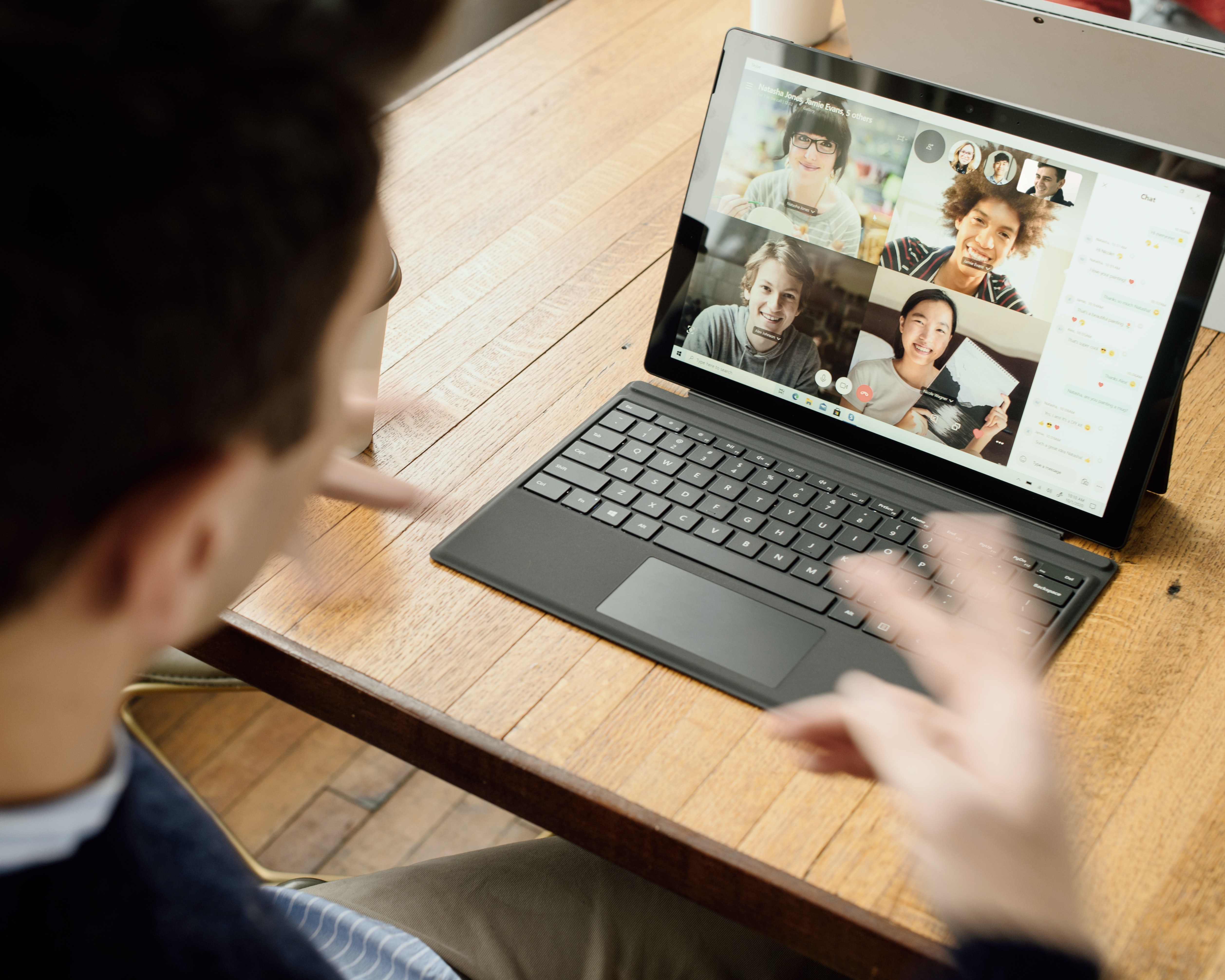 Person interacting with others on a video conference call as viewed from behind their head.